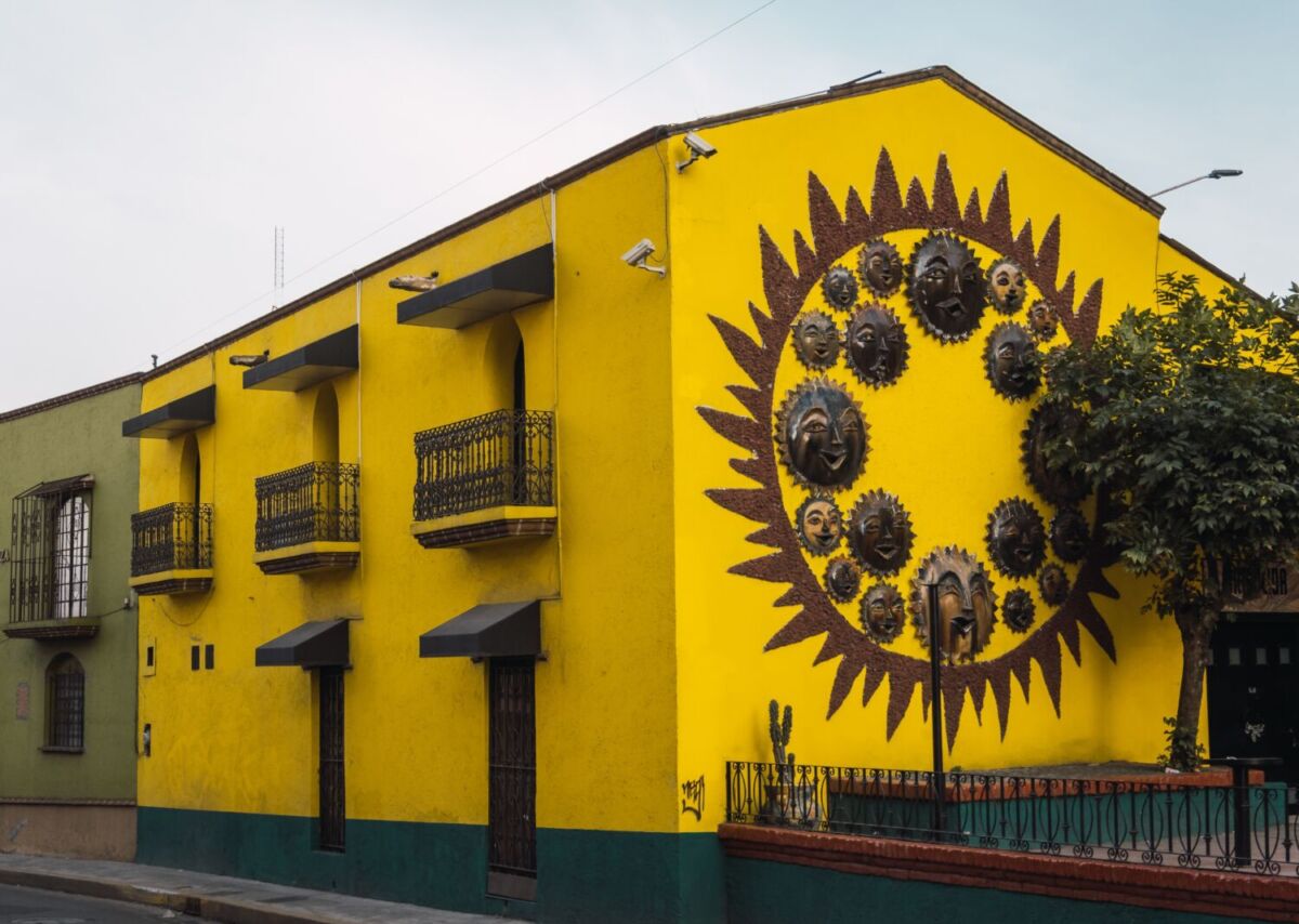 Fachada amarilla en Metepec con mural de sol hecho con máscaras de barro cocido, ejemplo de la tradición alfarera del Pueblo Mágico más pequeño de México