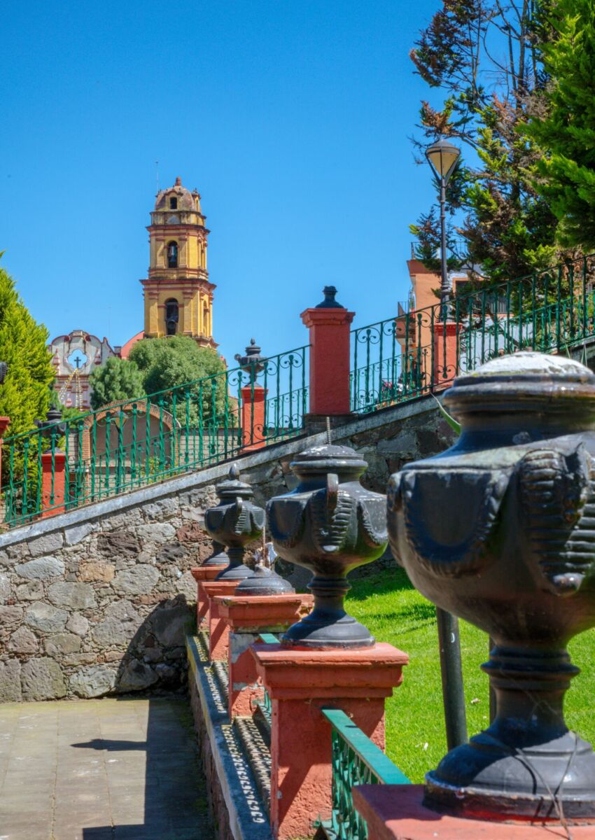 Vista de la Iglesia de San Juan Bautista en Metepec desde los jardines del Cerro de los Magueyes, con jarrones artesanales de barro en primer plano
