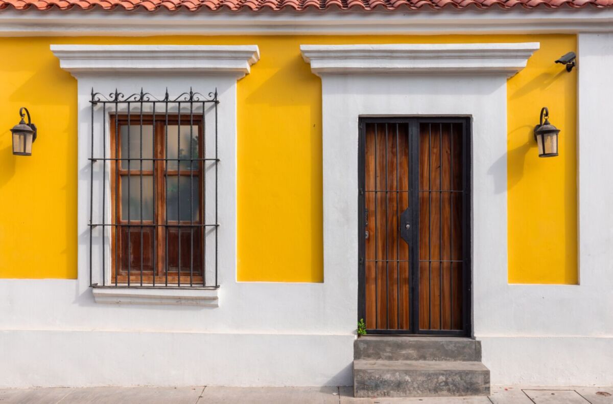 Fachada color amarillo con puerta de madera y ventana en el centro histórico de Mazatlán.