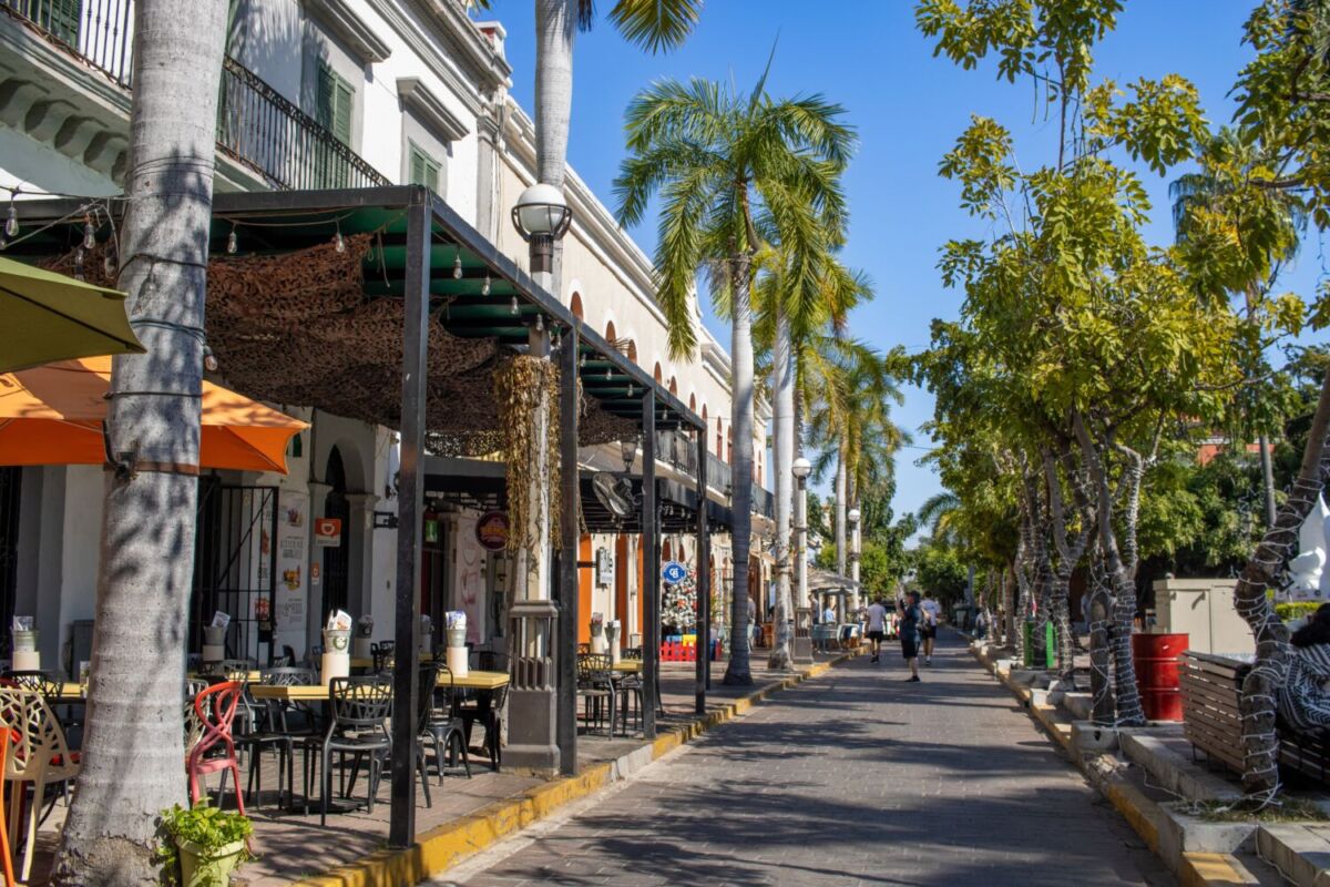 Calle con restaurantes y palmeras en el centro histórico de Mazatlán cerca del malecón.