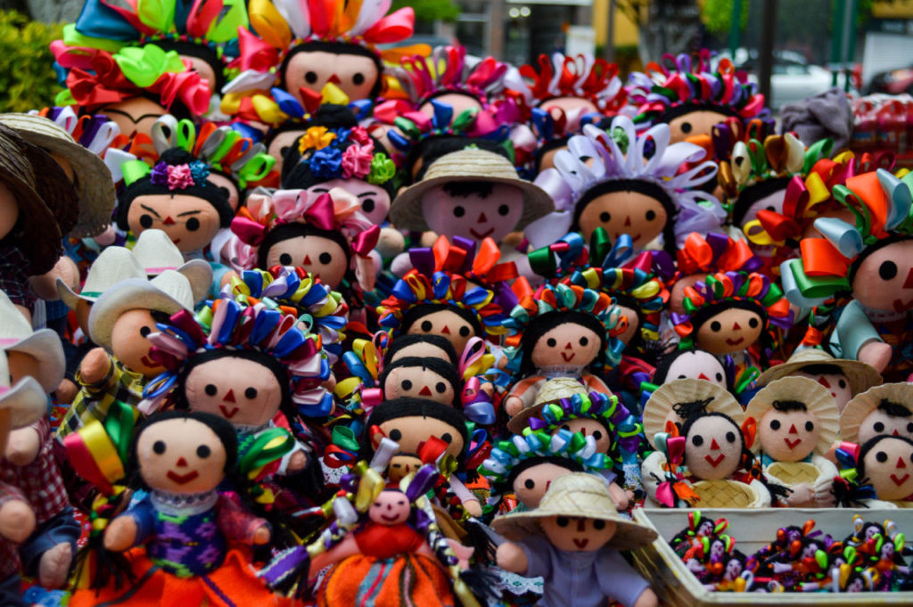 Muñecas artesanales mexicanas de tela con listones de colores en mercado tradicional en México.