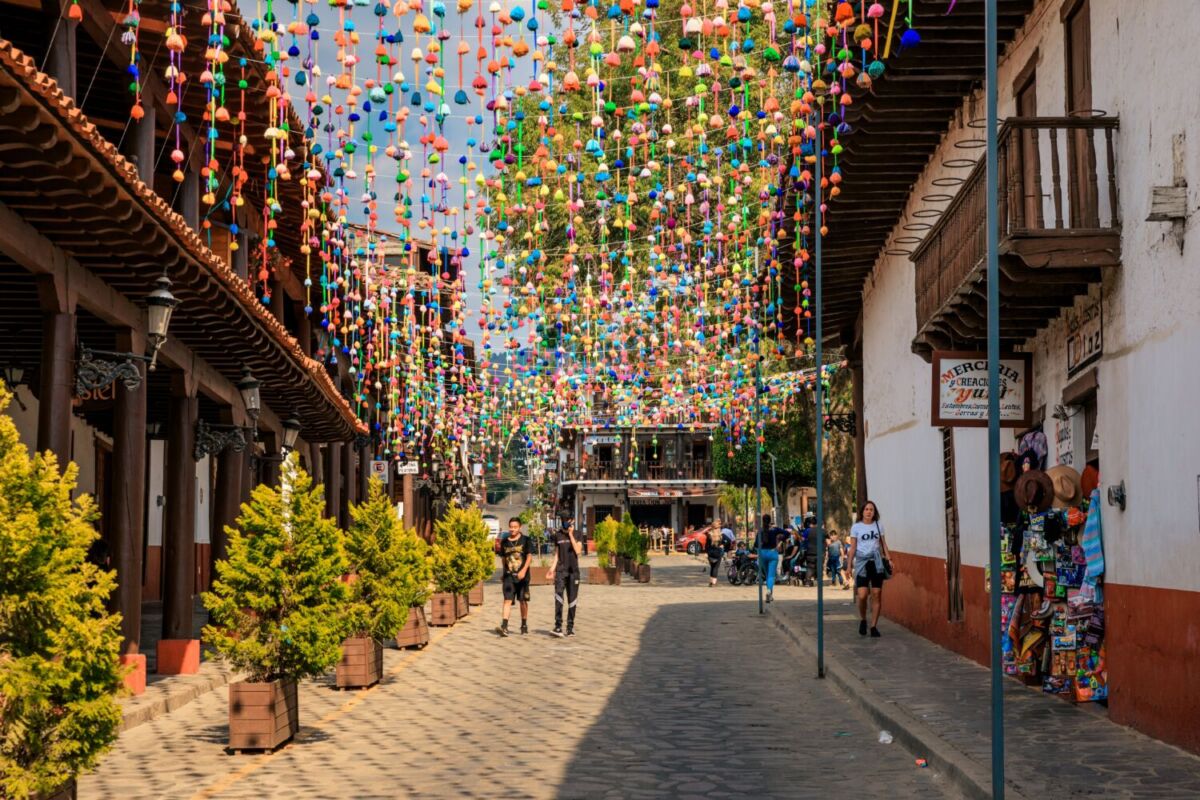 personas caminando por una calle decorada con pompones