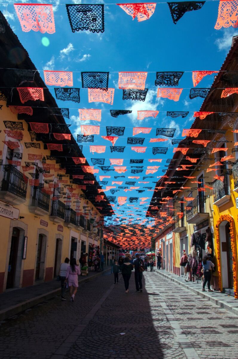 Calle de Real del Monte decorada con papel picado de Día de Muertos entre fachadas coloniales, Hidalgo