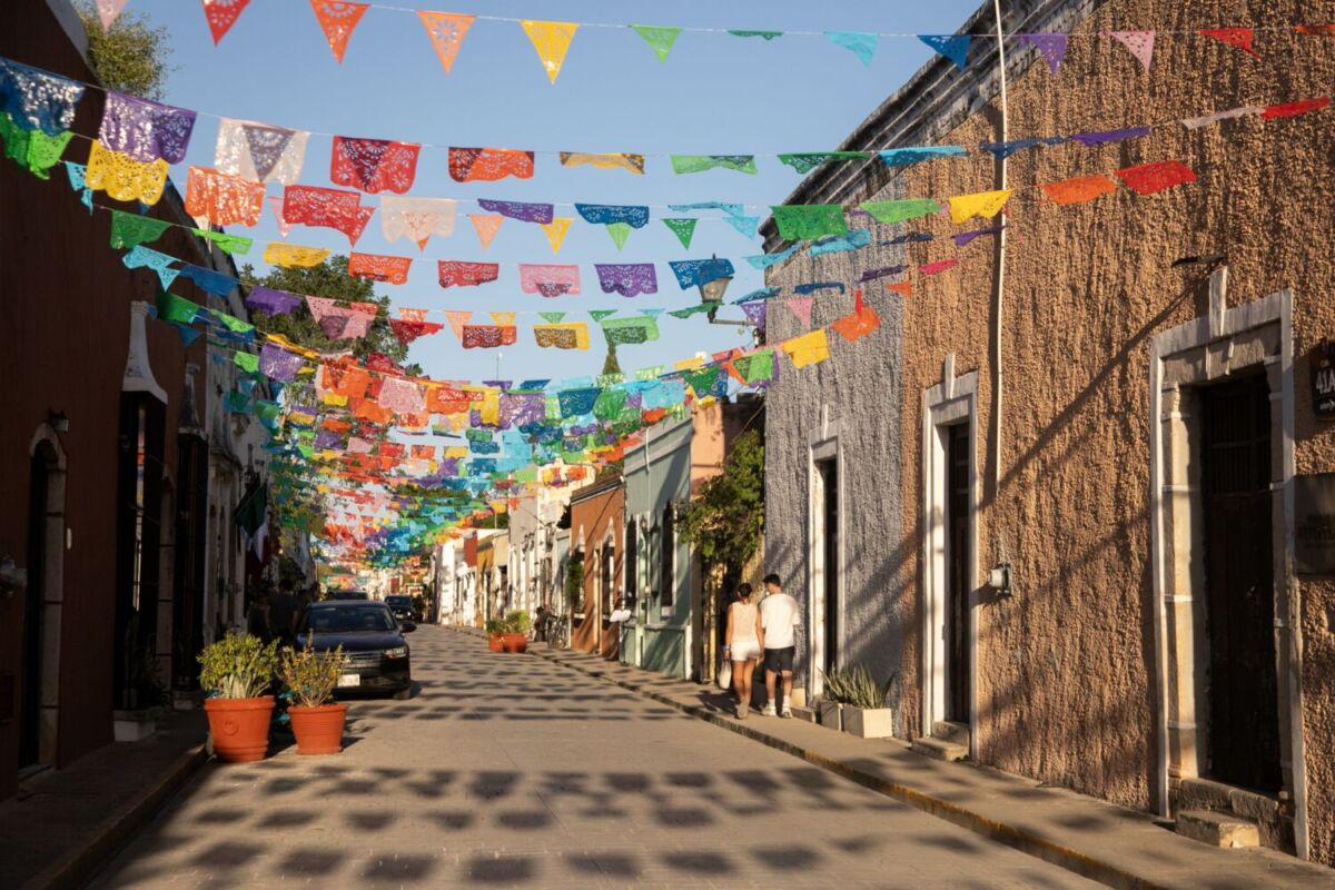 Calle de Valladolid decorada con papel picado de colores sobre fachadas coloniales