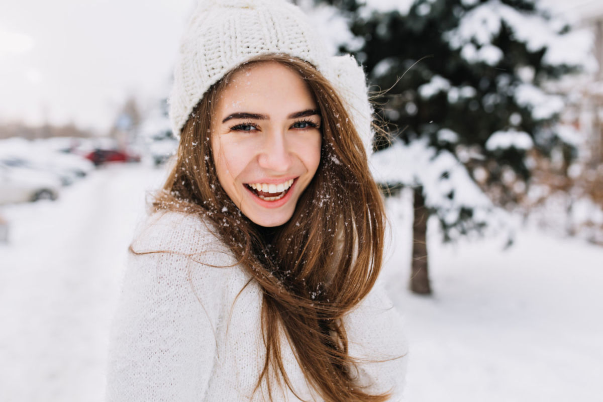 Mujer joven sonriendo en destino de nieve. 