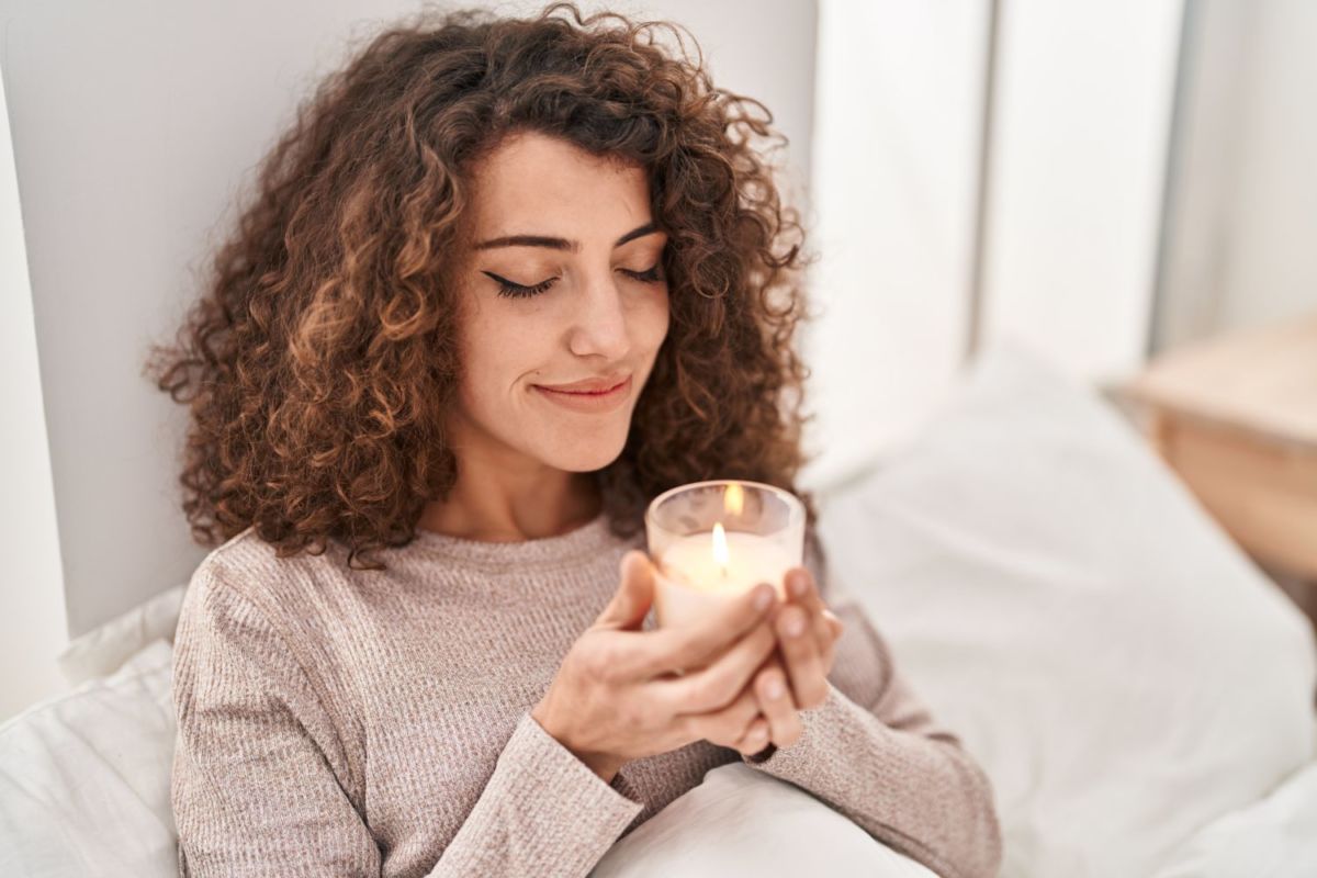Mujer apreciando el olor de su vela aromática.