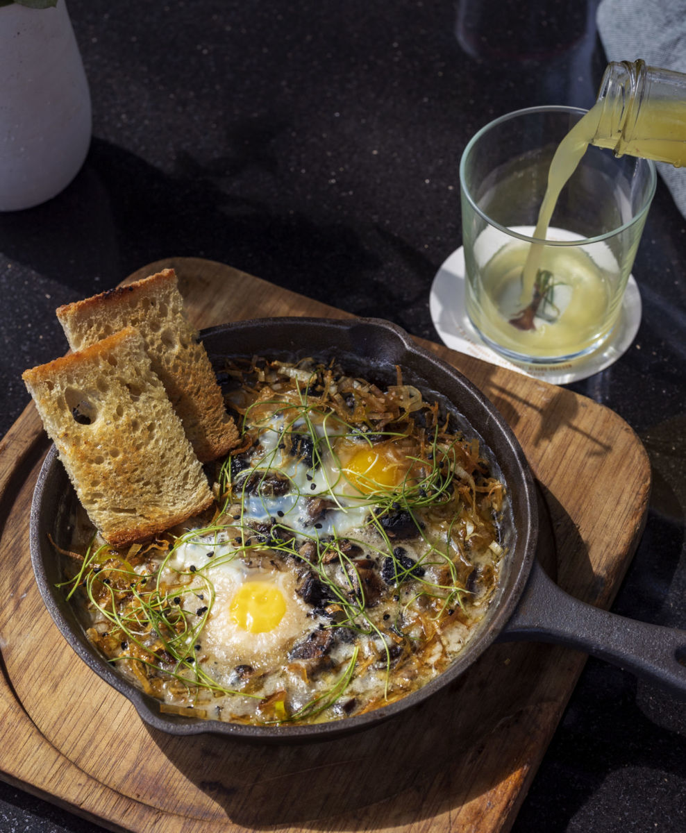 Cazuela de huevos pochados con salsa de quesos, poro frito y pan de masa madre