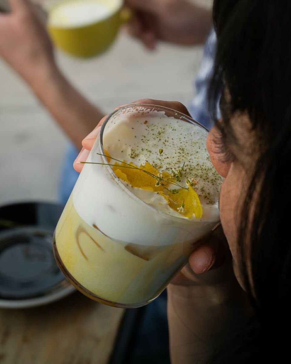 mujer bebiendo una bebida con espuma decorada con flores