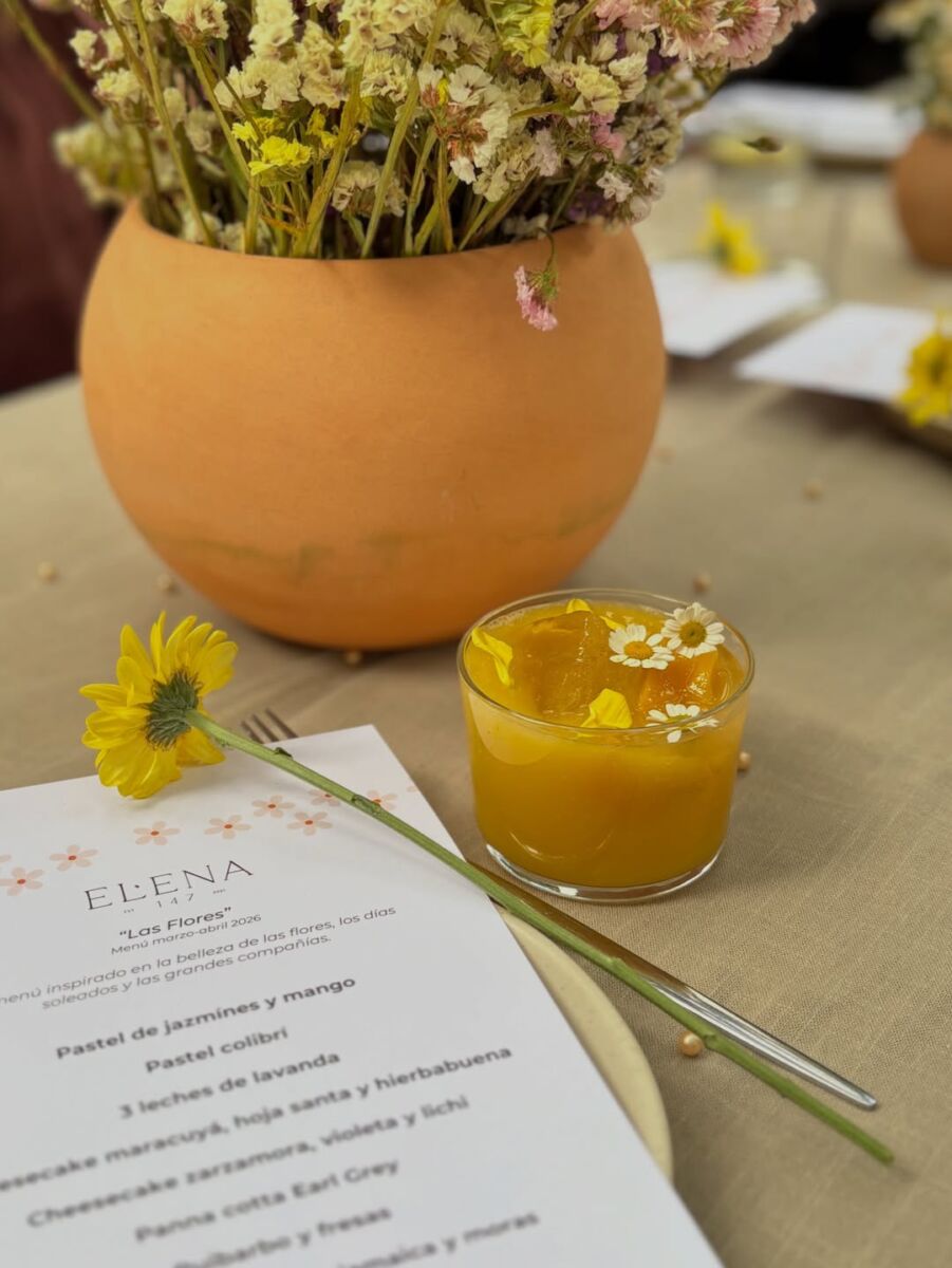bebida de mango decorada con flores junto a un jarrón de flores de manzanilla