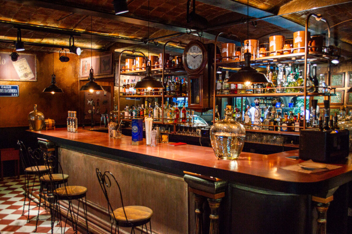 barra de madera en una cantina clásica, con bancos altos y botellas en una repisa