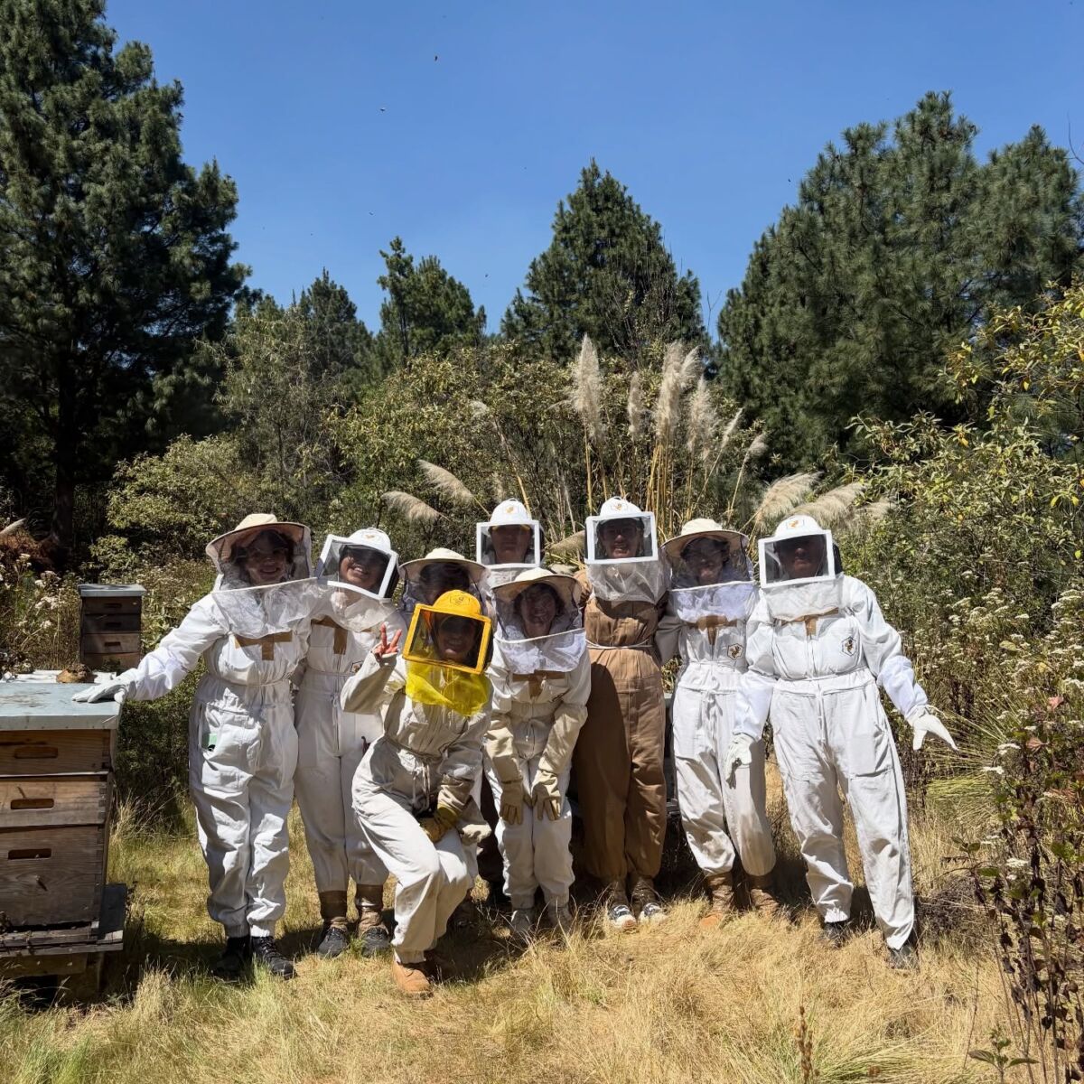 grupo de personas con trajes de apicultores posando para la cámara en medio del campo