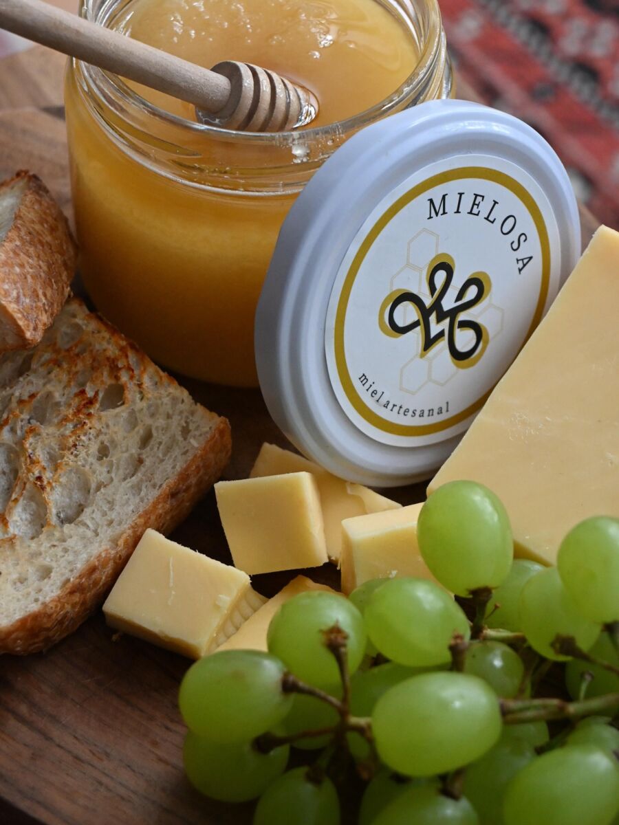 toma cerrada de un frasco de miel abierto, uvas, pan y queso