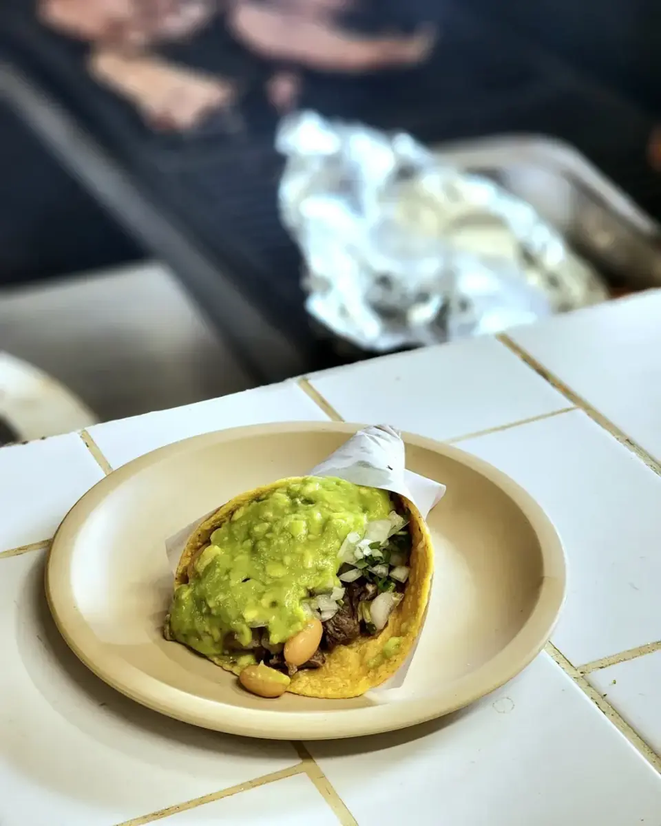 taco de carne asada servido en torilla de maíz, con guacamole y frijoles 