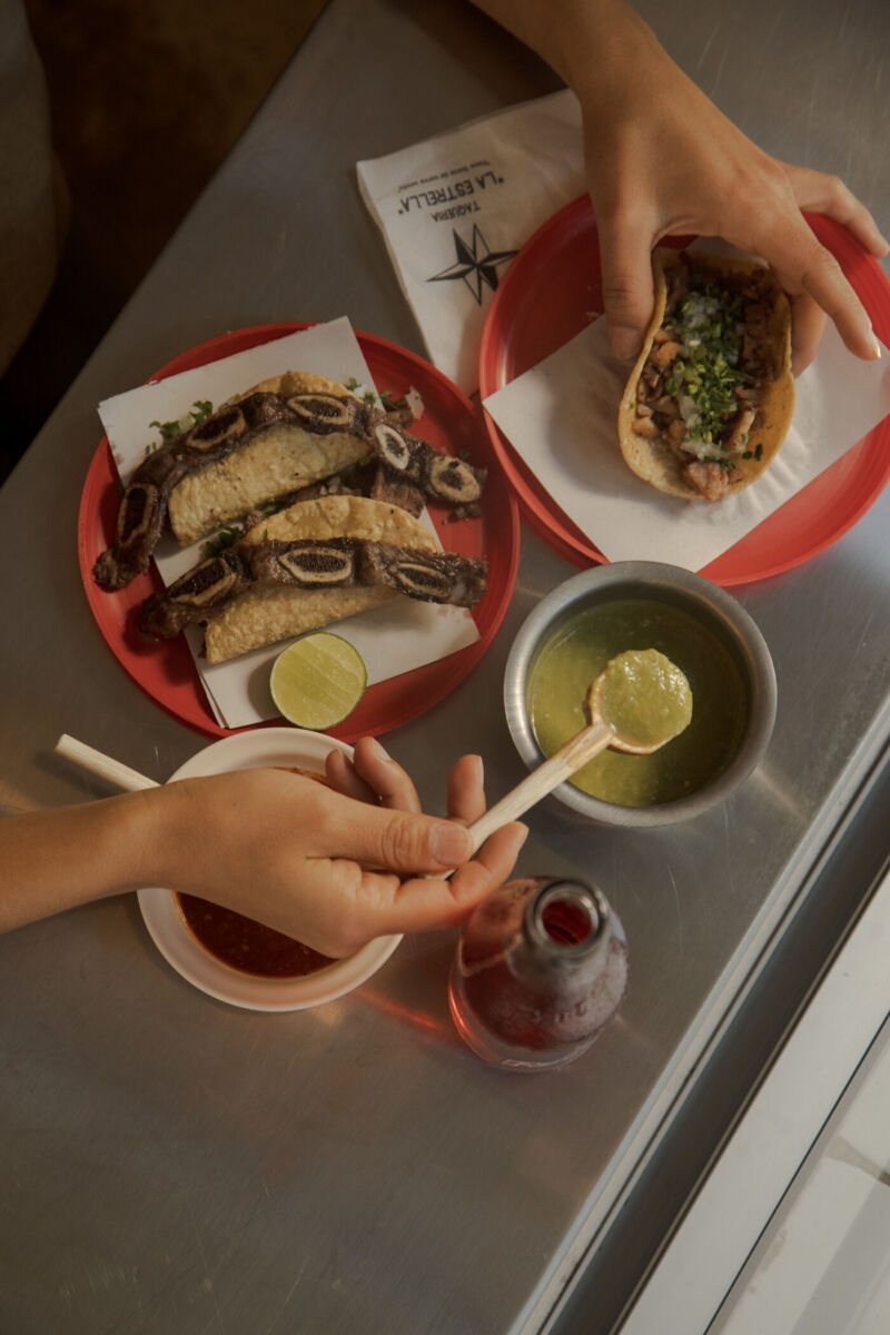 Persona poniendo salsa verde a un taco de carne asada 