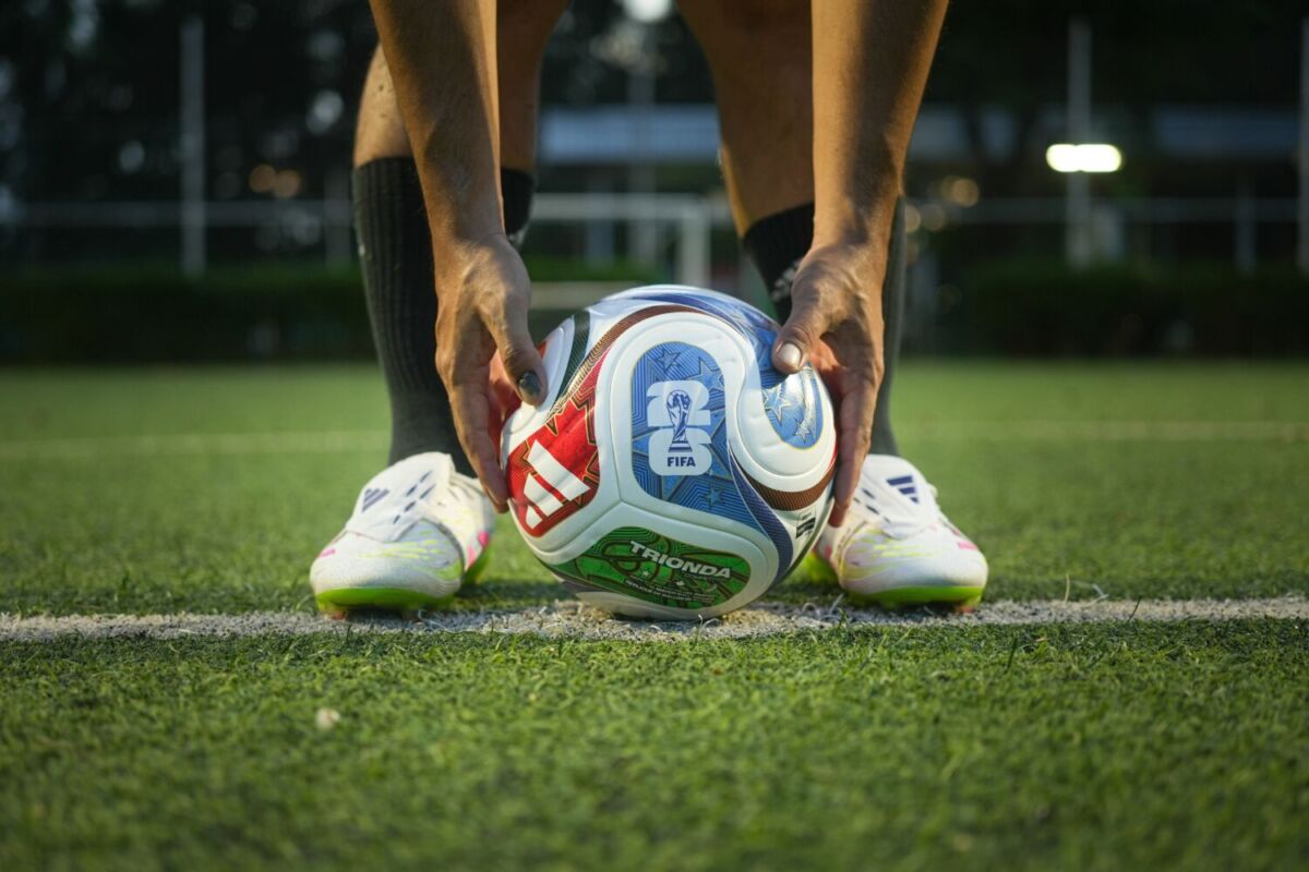 Hombre sujetando un balón de futbol en un estadio. 

