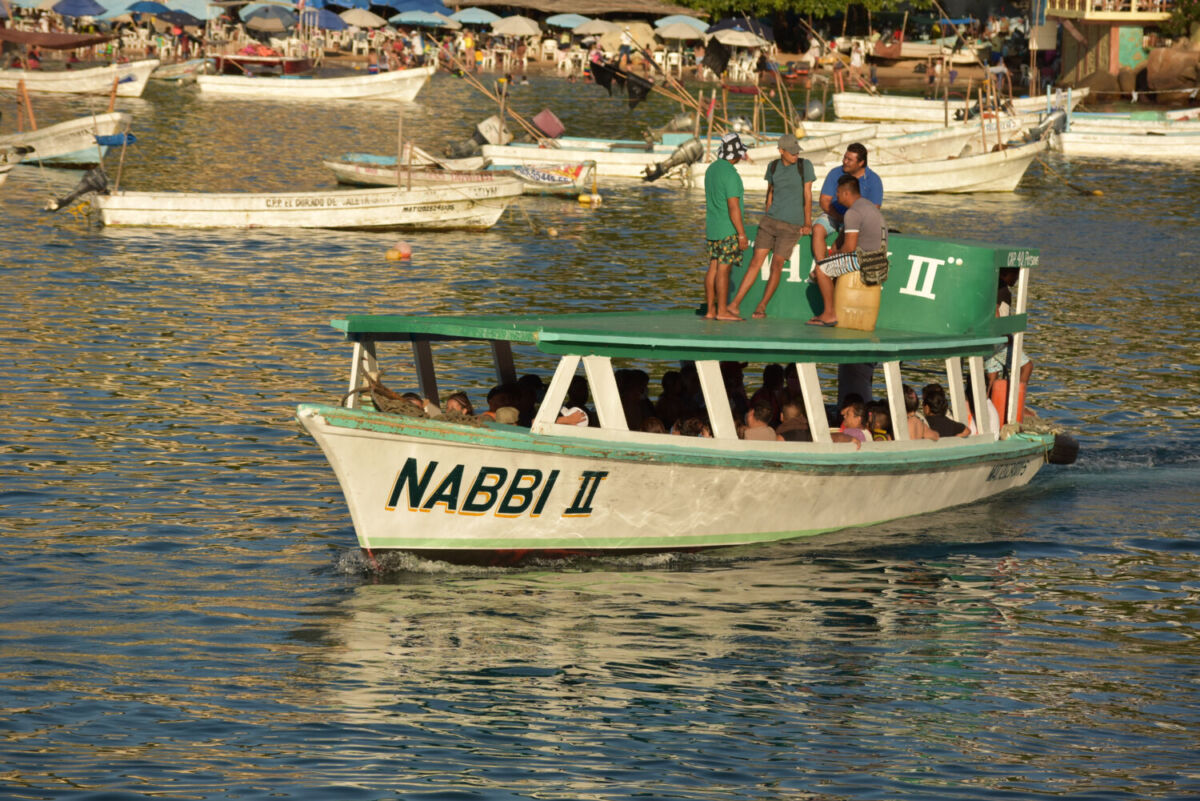 bote blanco con techo verde con gente a bordo y pesonas paradas en el techo