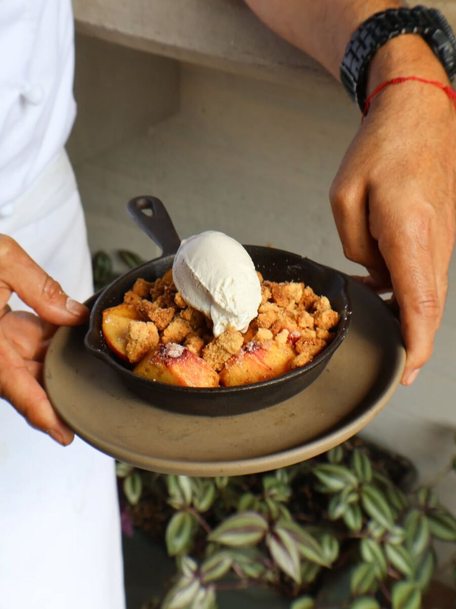 crumble de durazno con helado de vainilla servido en una sartén de hierro