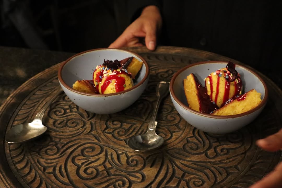 dos platos de helado de mango con salsa roja, chispas de colores y panqué de elote