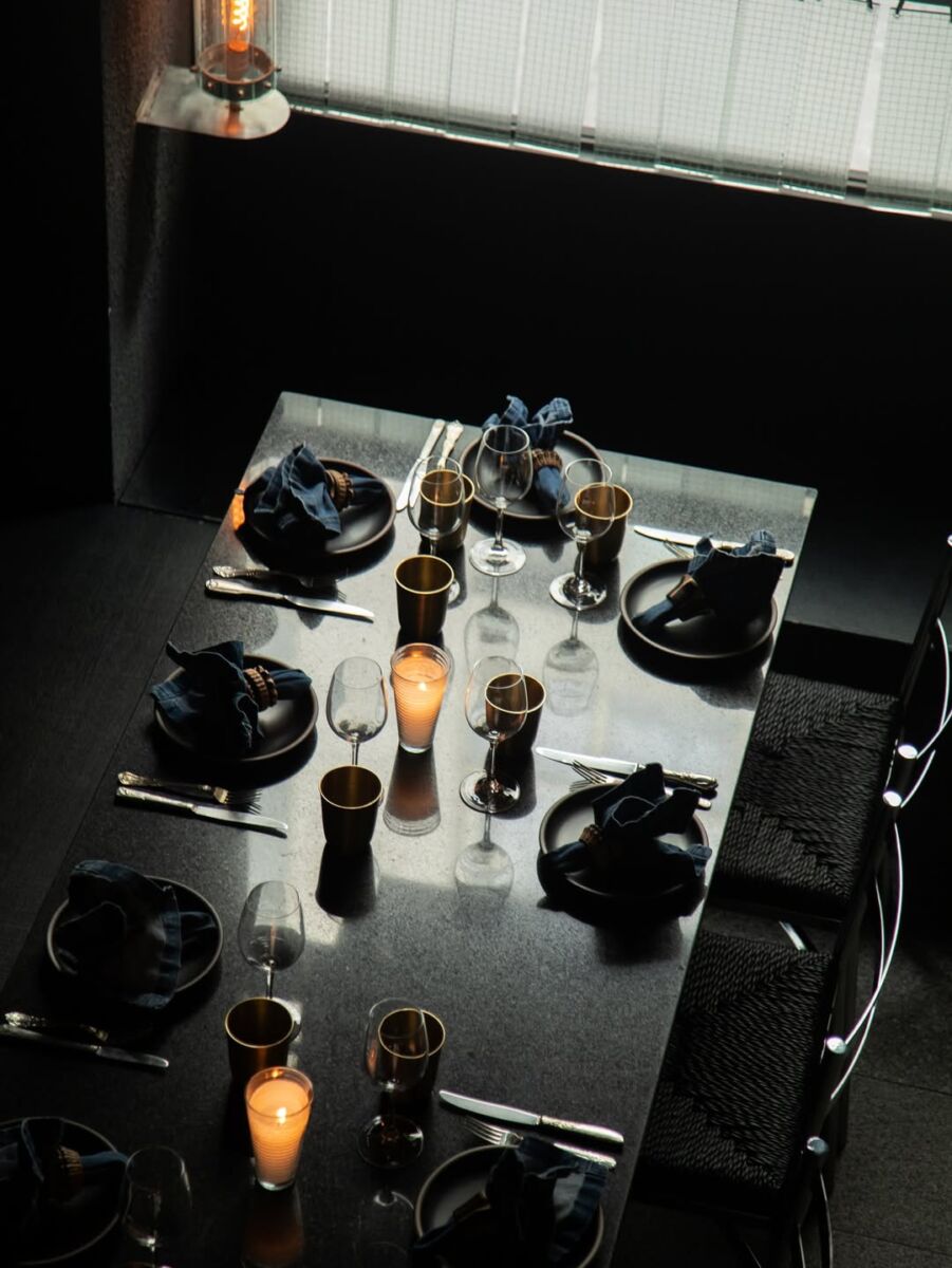 toma desde arriba de una mesa puesta para seis personas, iluminada a la luz de las velas con estética moderna y minimalista
