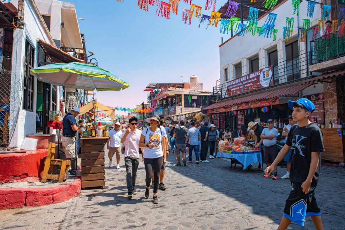 personas caminando por un pintoresco pueblo mexicano 
