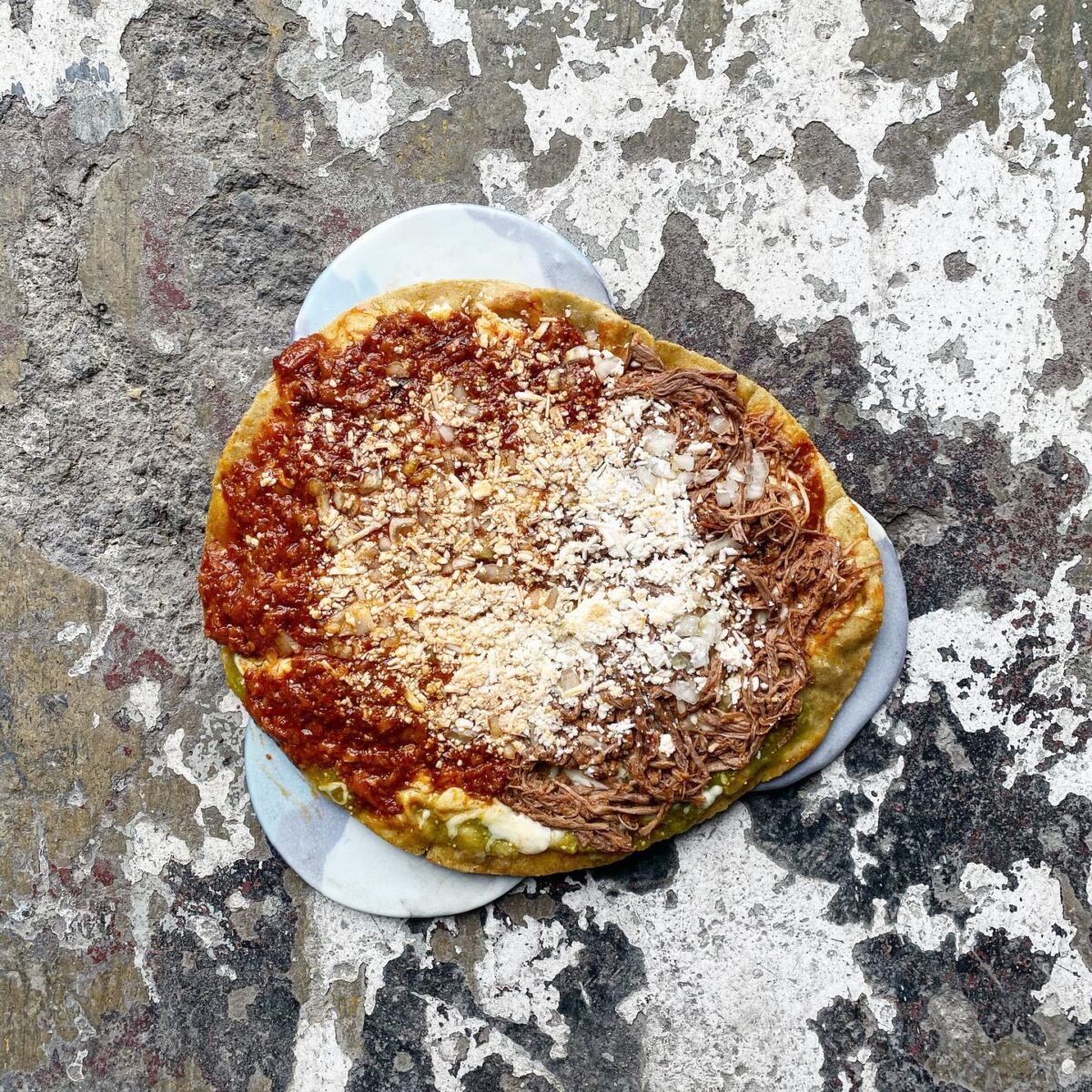 antojito mexicano de maíz, frijoles, salsa, queso y guisado