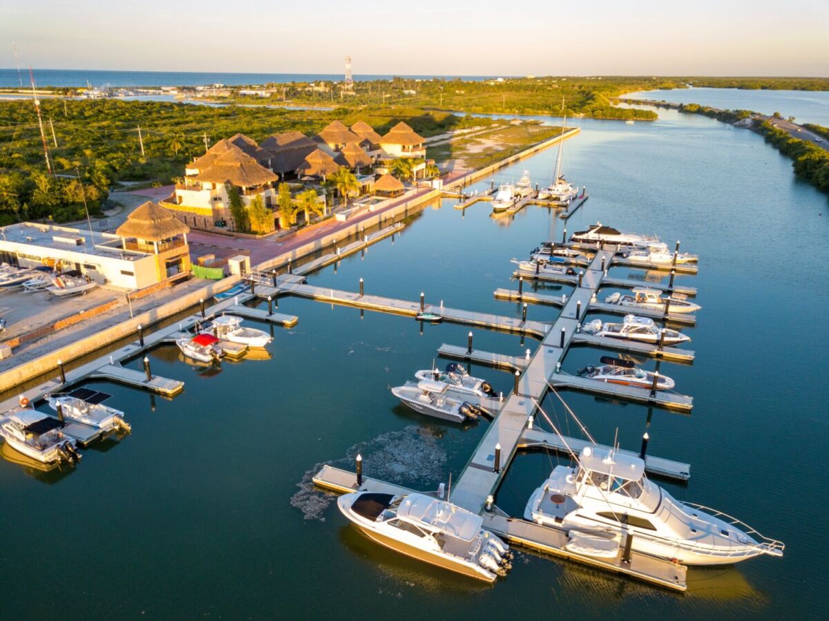 toma aérea de una marina con yates y un paisaje tropical detrás