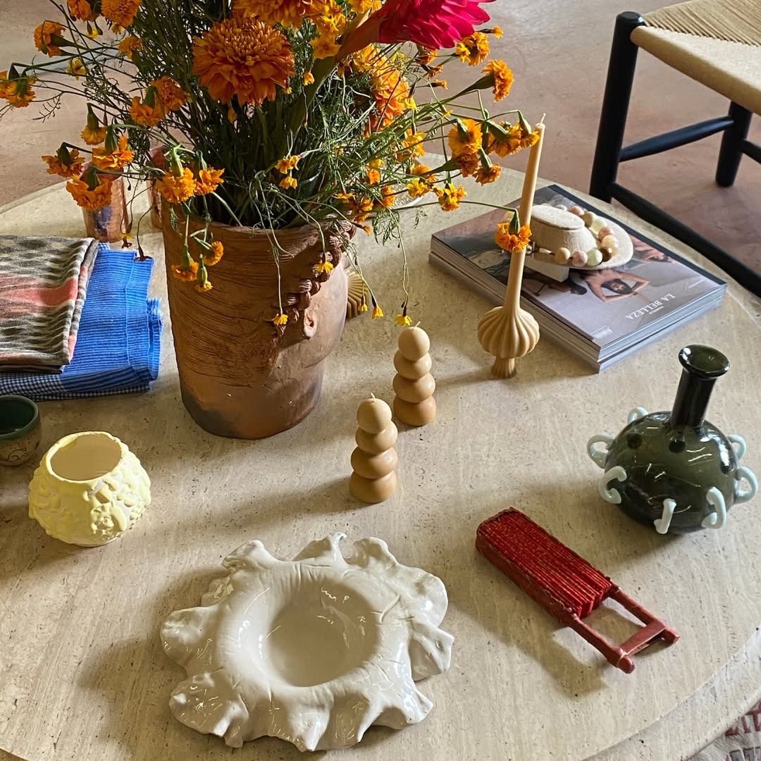 mesa con mantel blanco y flores y cosas de ceramica encima