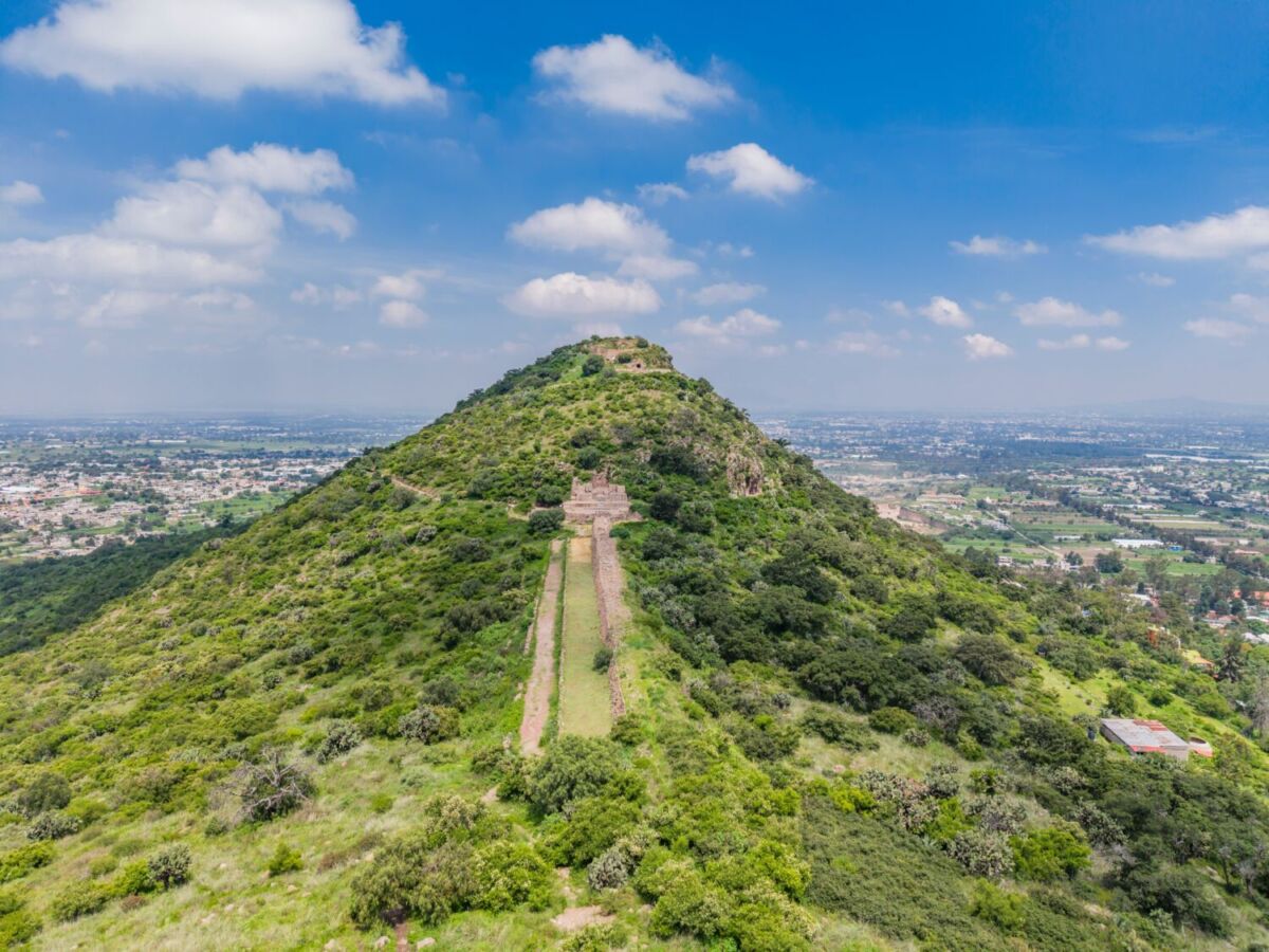 Vista aérea del cerro Tetzcotzinco con ruinas de los Baños de Nezahualcóyotl y vista panorámica del Valle de México, TexcocoLeyenda: Vista aérea del cerro Tetzcotzinco donde Nezahualcóyotl construyó su jardín botánico y sistema hidráulico entre 1431 y 1466, a una hora de CDMX.