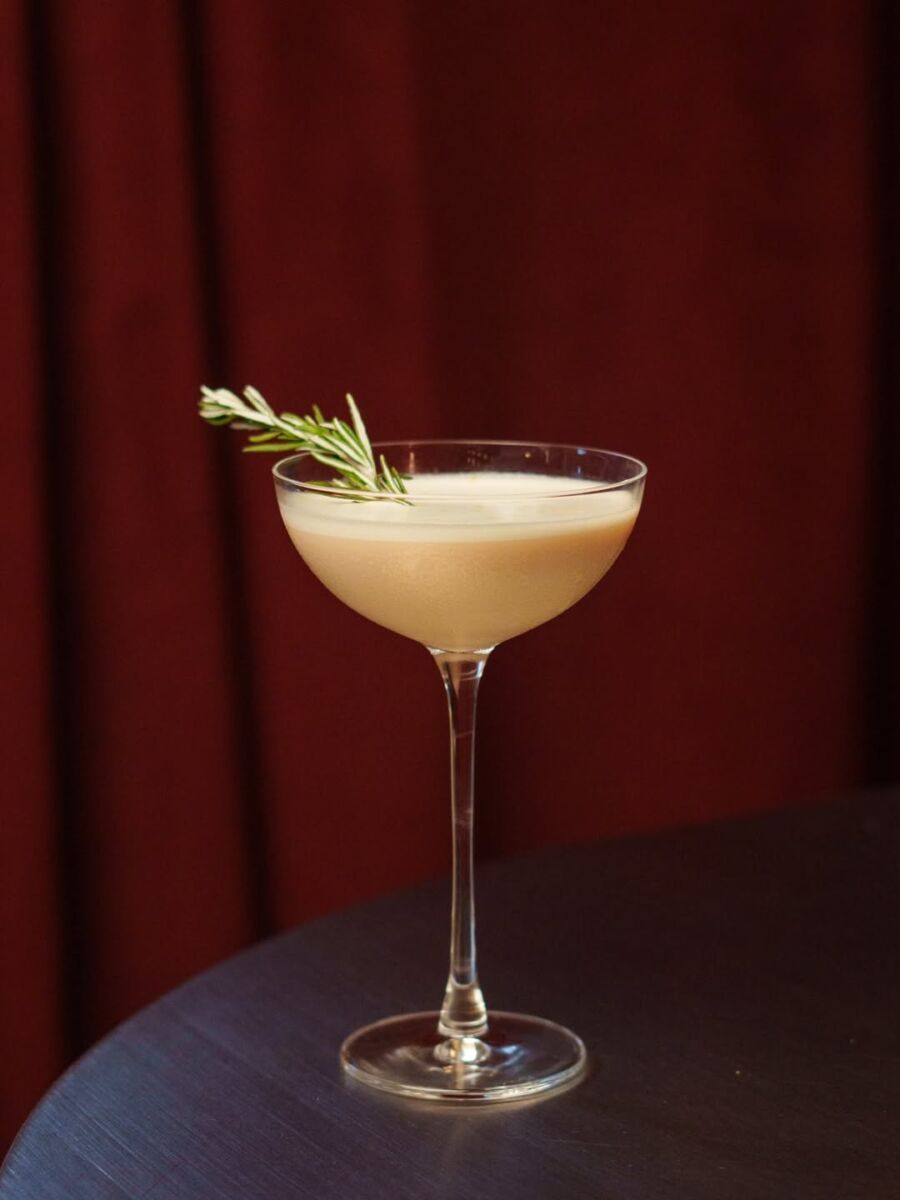 coctel color amarillo en una copa de cristal elegante decorado con romero