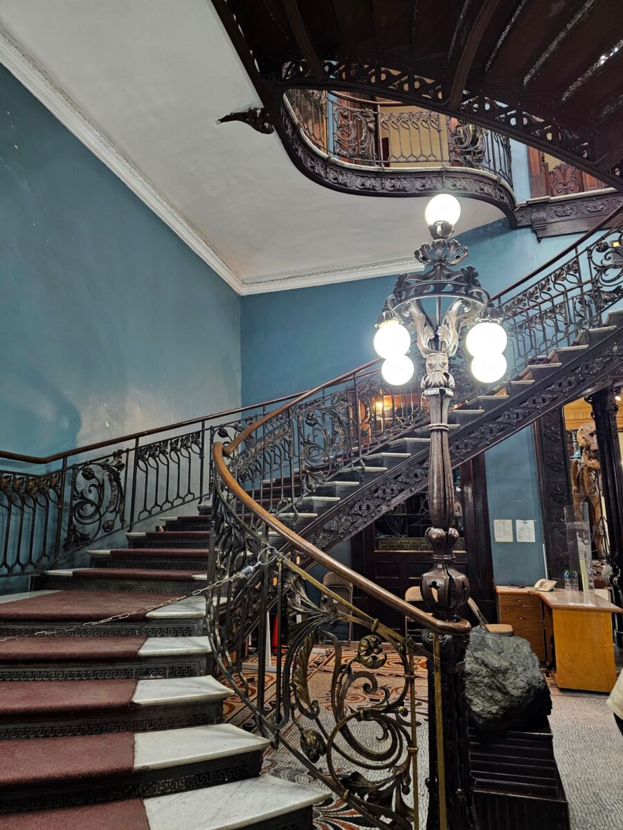 Escalera de mármol con barandal de herrería art nouveau en edificio porfiriano de Santa María la Ribera, CDMX.
