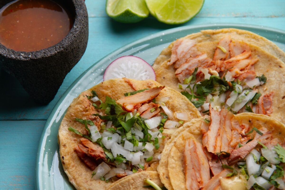 plato con tacos al pastor, servidos con cebolla y cilantro 