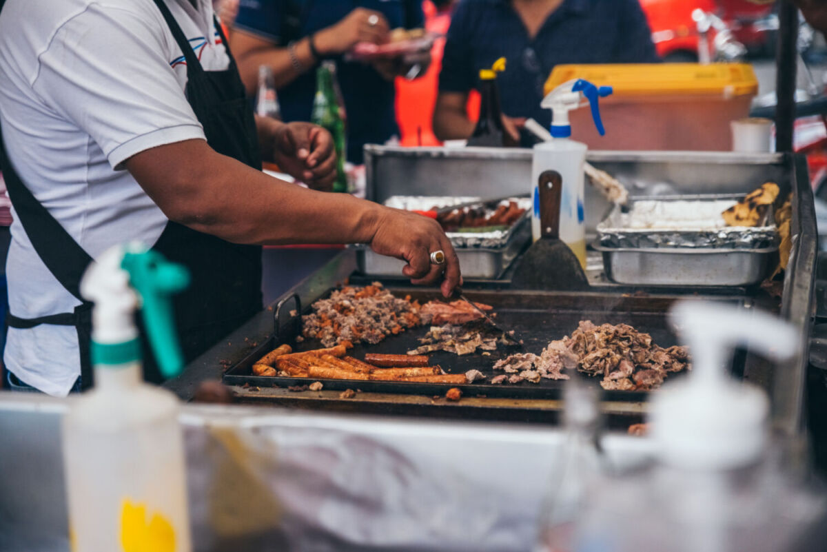 un hombre preparando tacos en el brasero 