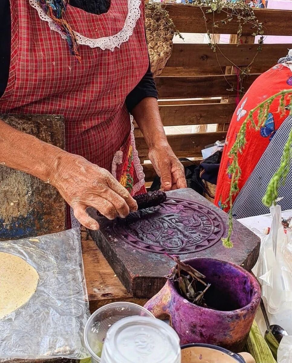mujer mayor entintando un sello de madera para tortillas