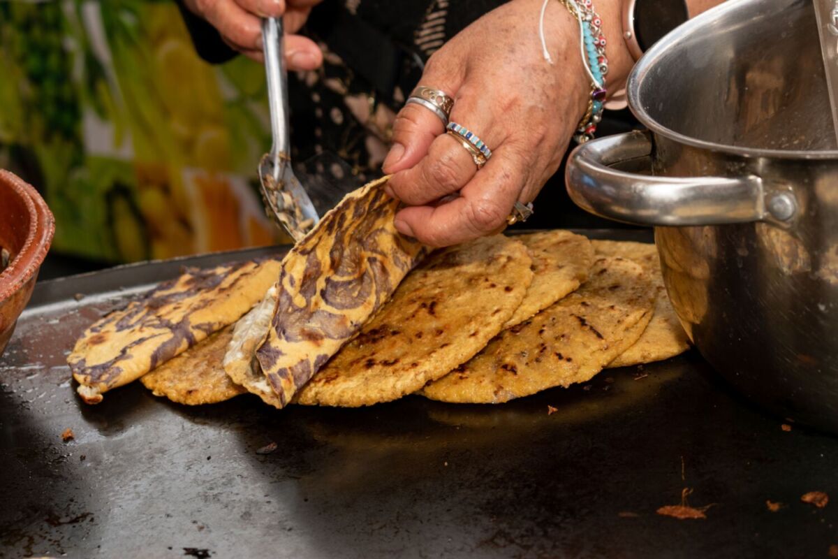 close up de unas manos haciendo quesadillas con tortillas ceremoniales