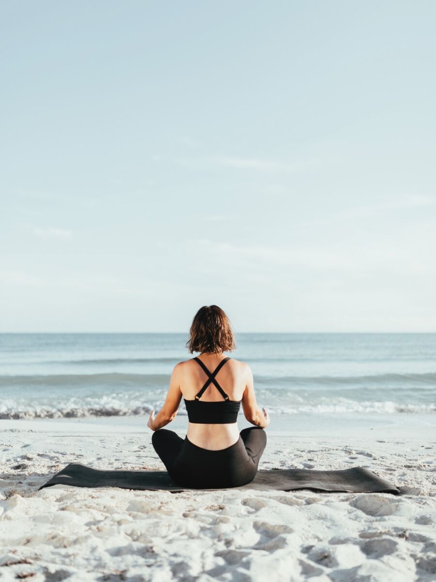 mujer haciendo yoga frente al mar