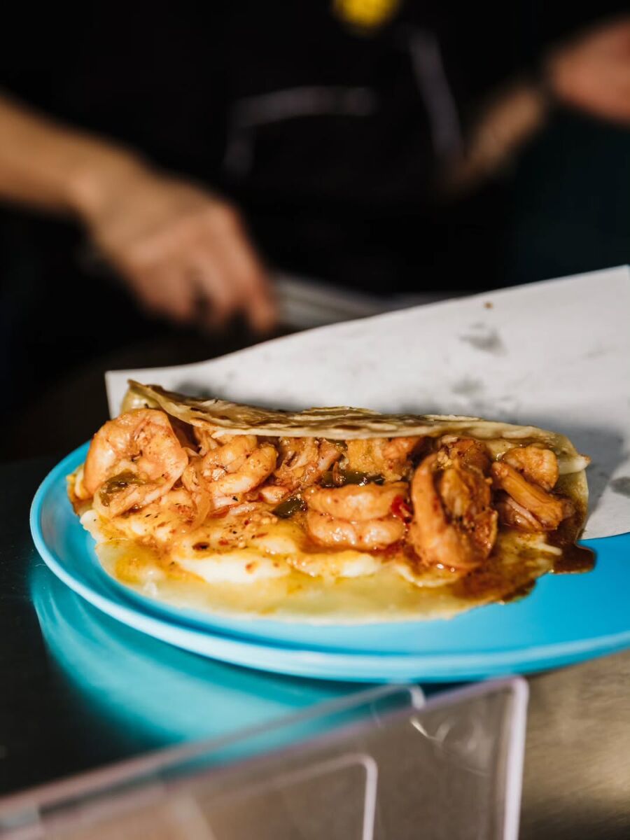taco de camarón enchilado en tortilla de maíz en plato azul de plástico