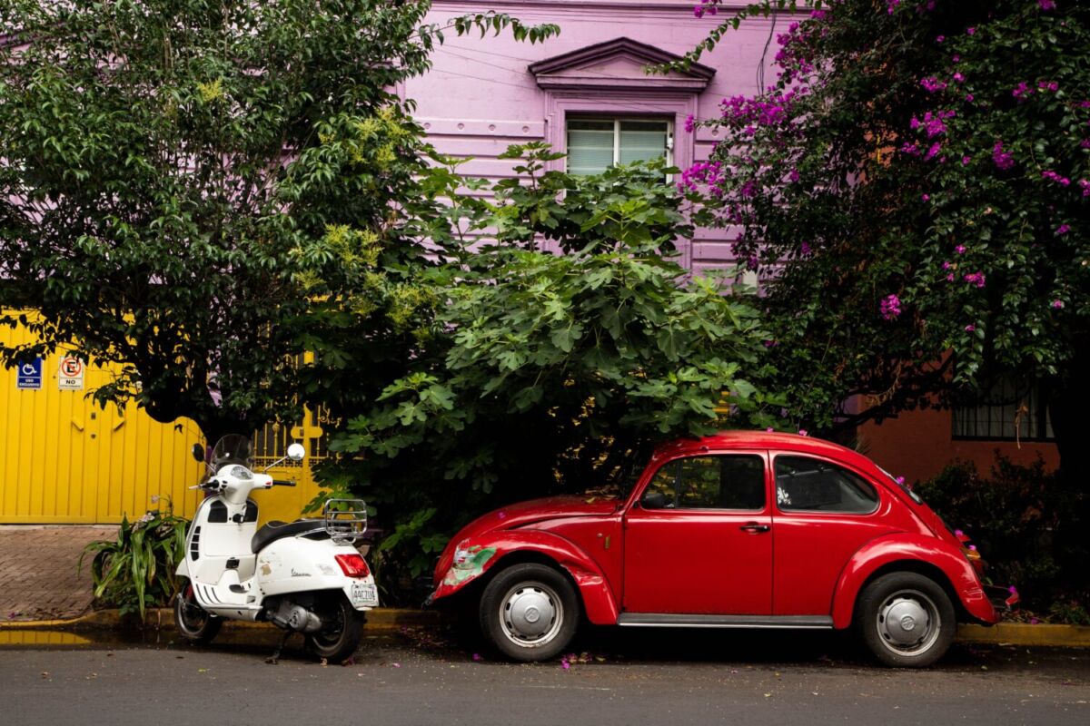fachada de una antigua casona, con motoneta y carro estacionados afuera 