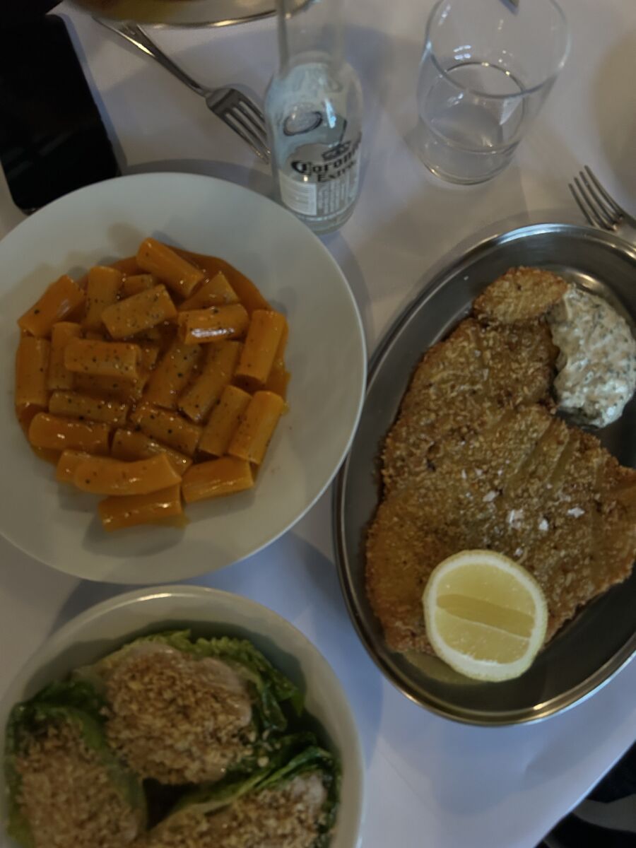 milanesa, pasta y ensalada César en la mesa 