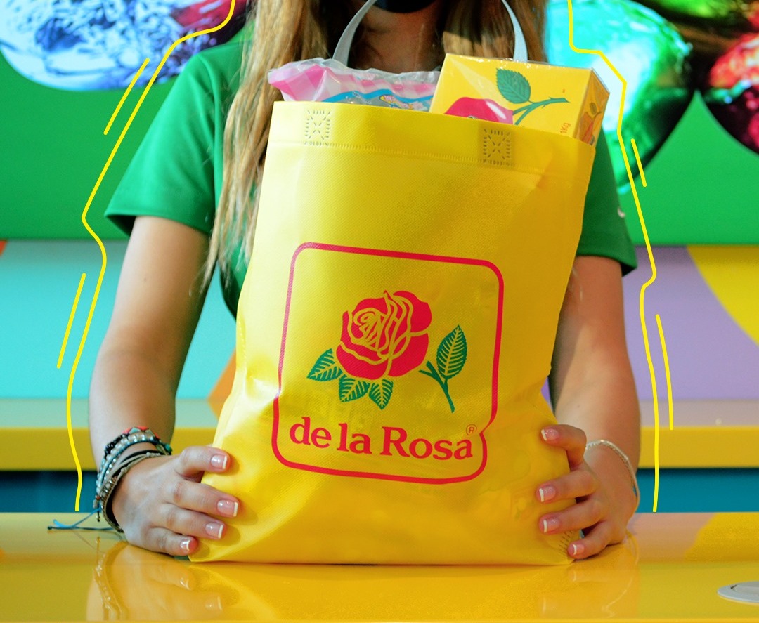 mujer sosteniendo una bolsa amarilla con el logotipo de Dulces De la Rosa llena de productos