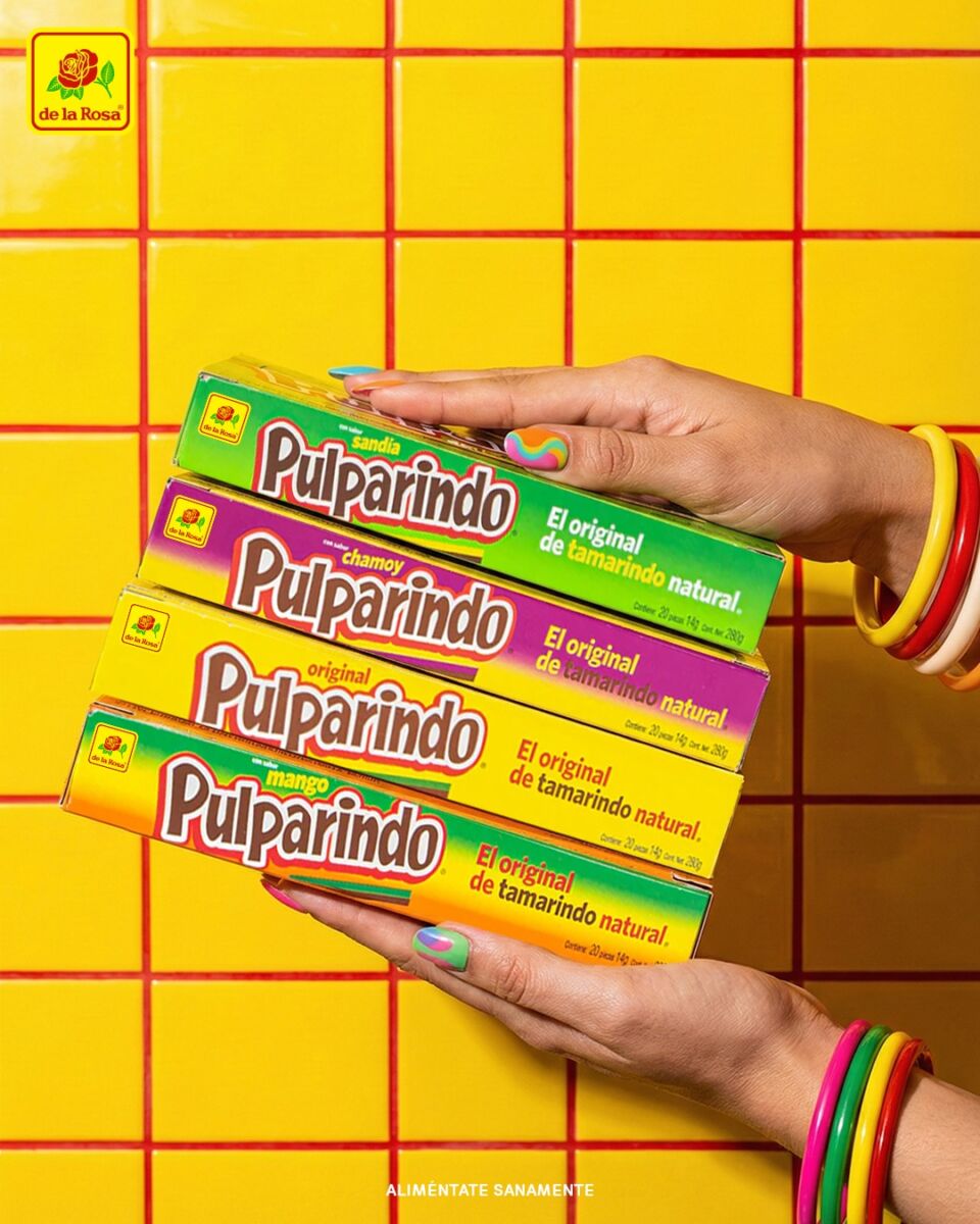 manos sosteniendo cuatro cajas de pulparindos frente a un fondo amarillo vibrante