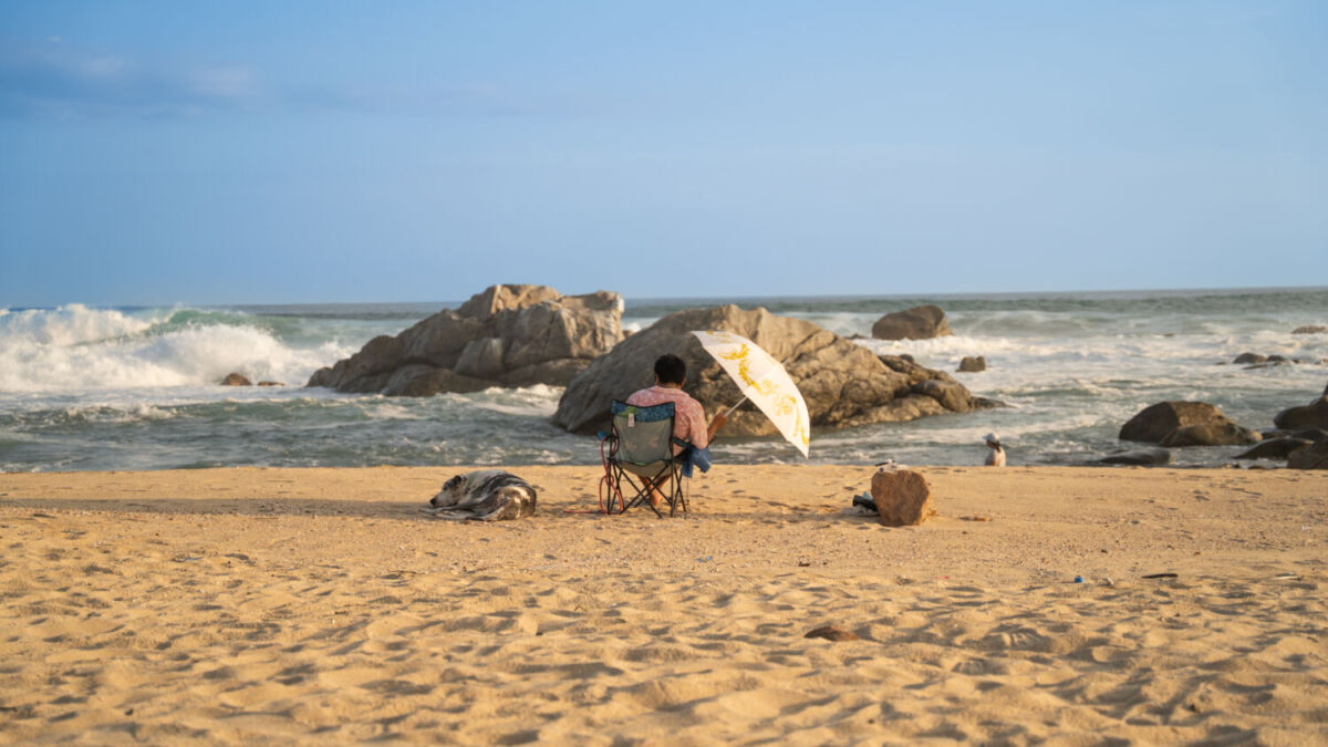 Persona sentada en la playa mirando el mar 