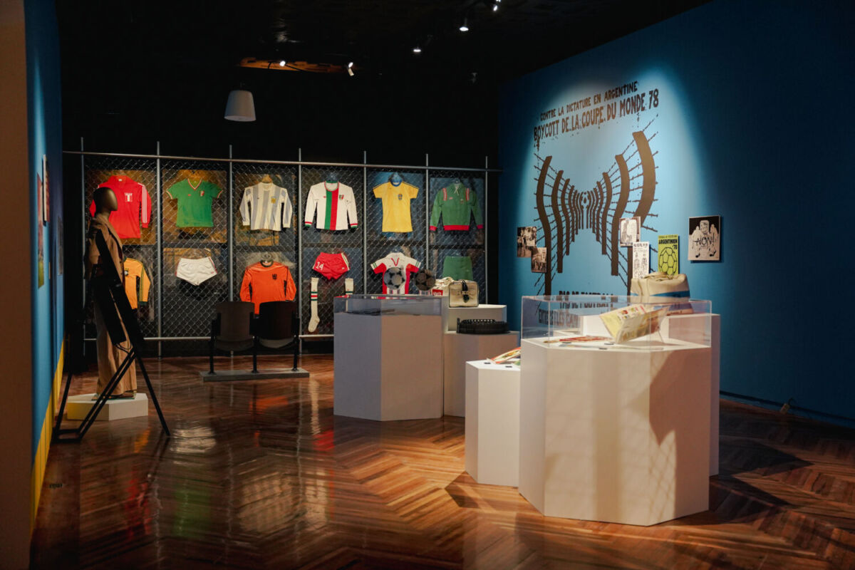 habitacion con muros azules, playeras de futbol colgadas en las paredes y pedestales blancos con distintos objetos