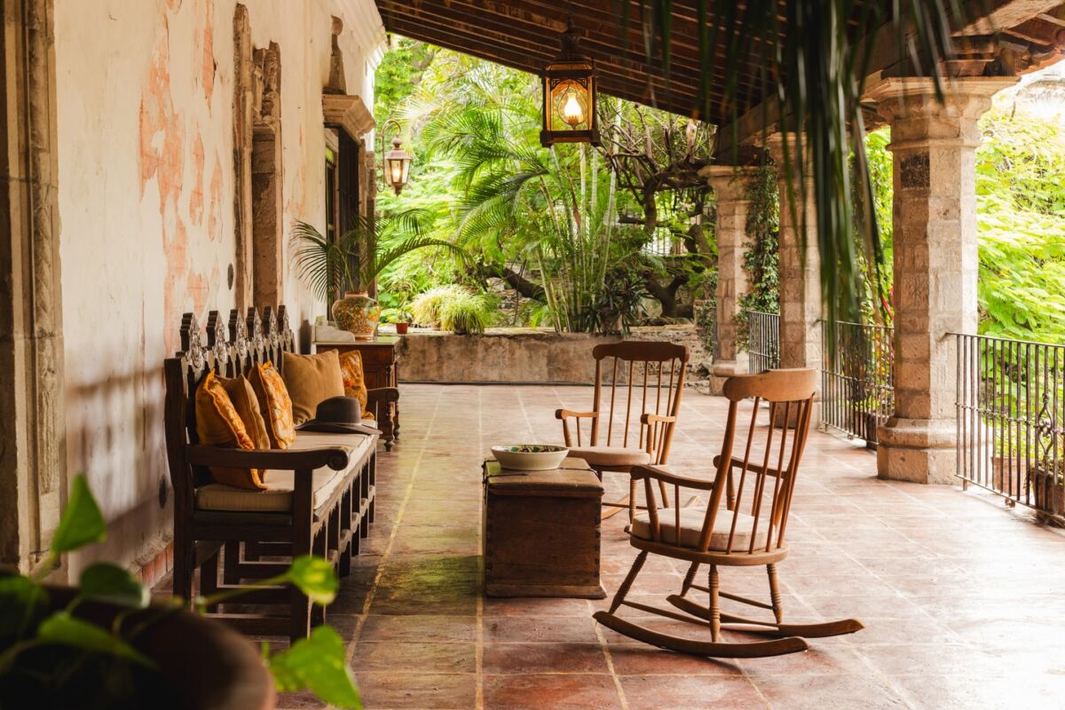 terraza exterior de una casona antigua con mecedoras y muebles de madera