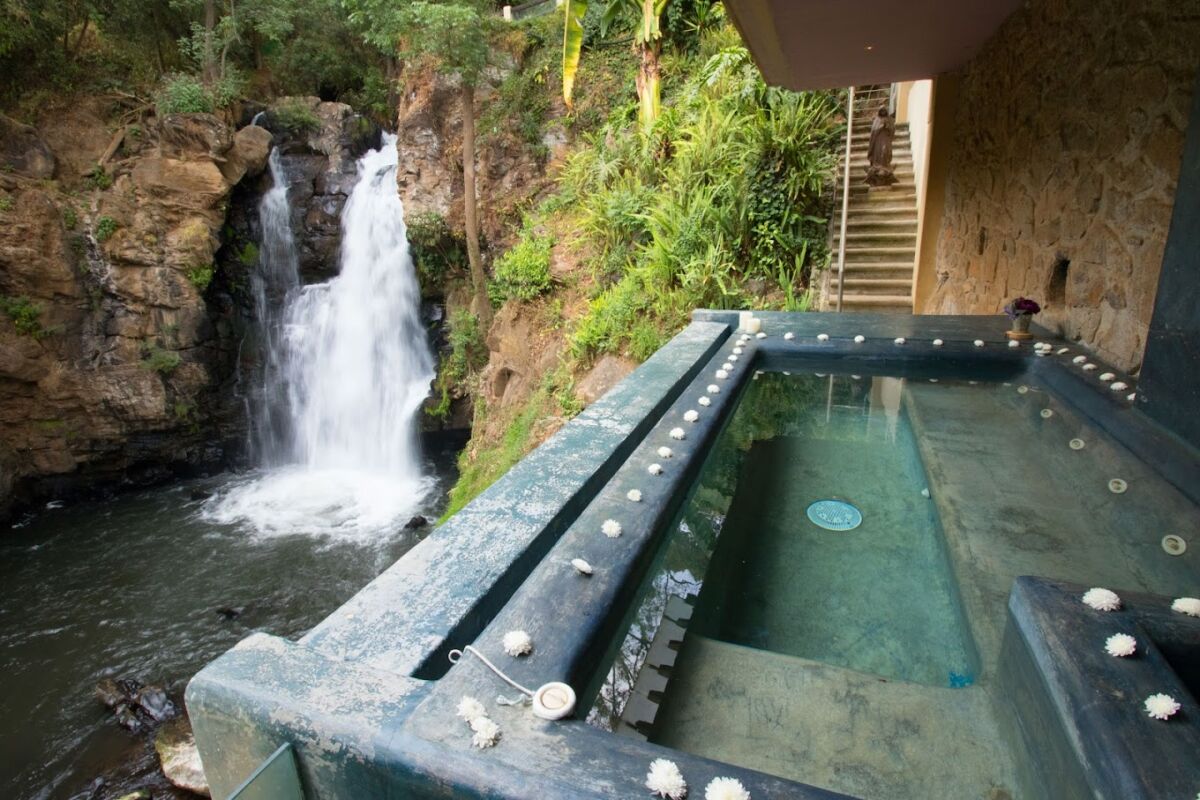 jacuzzi al aire libre frente a una cascada natural 