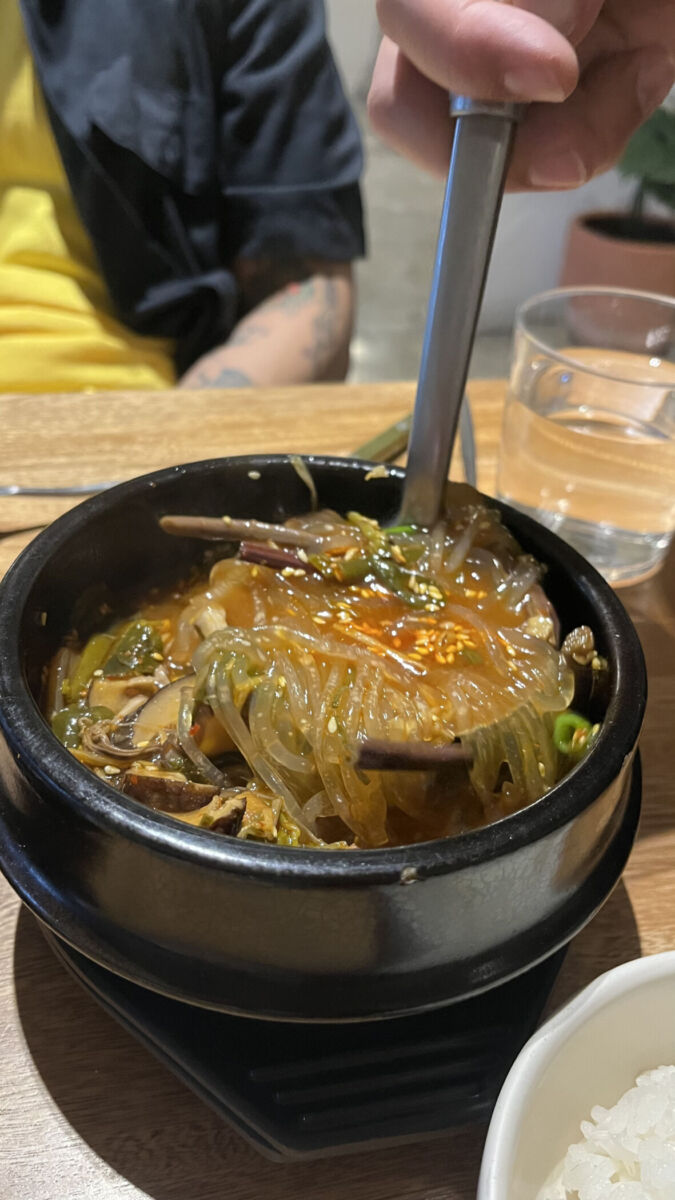 cucharón revolviendo caldo asiático con fideos y verduras