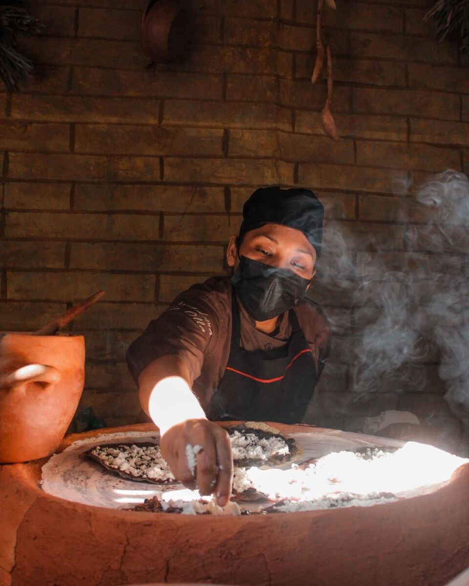 mujer cocinan tlayudas en un comal 