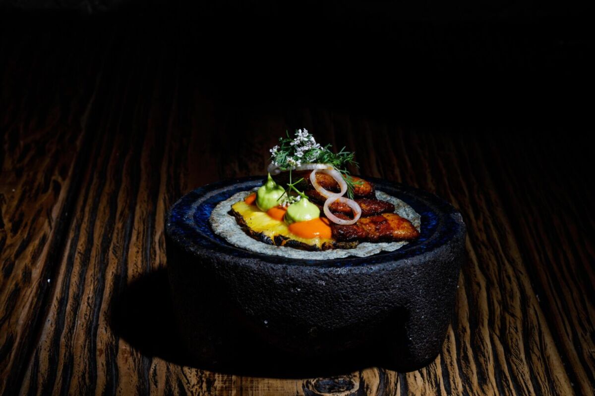 Taco de tortilla azul con pork belly glaseado y guacamole en molcajete negro en Limosneros restaurante Centro Histórico CDMX