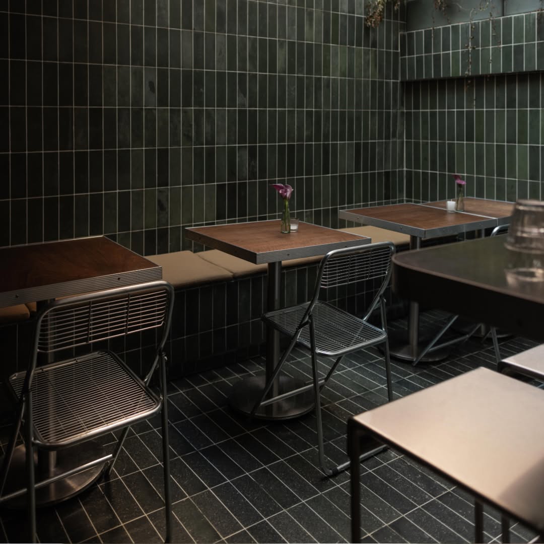 mesas y sillas en una habitación con azulejos verdes 