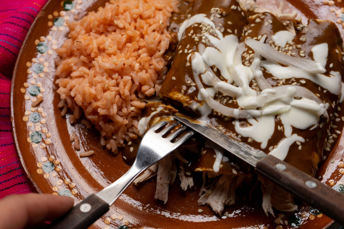 persona comiendo enchiladas de mole con arroz 