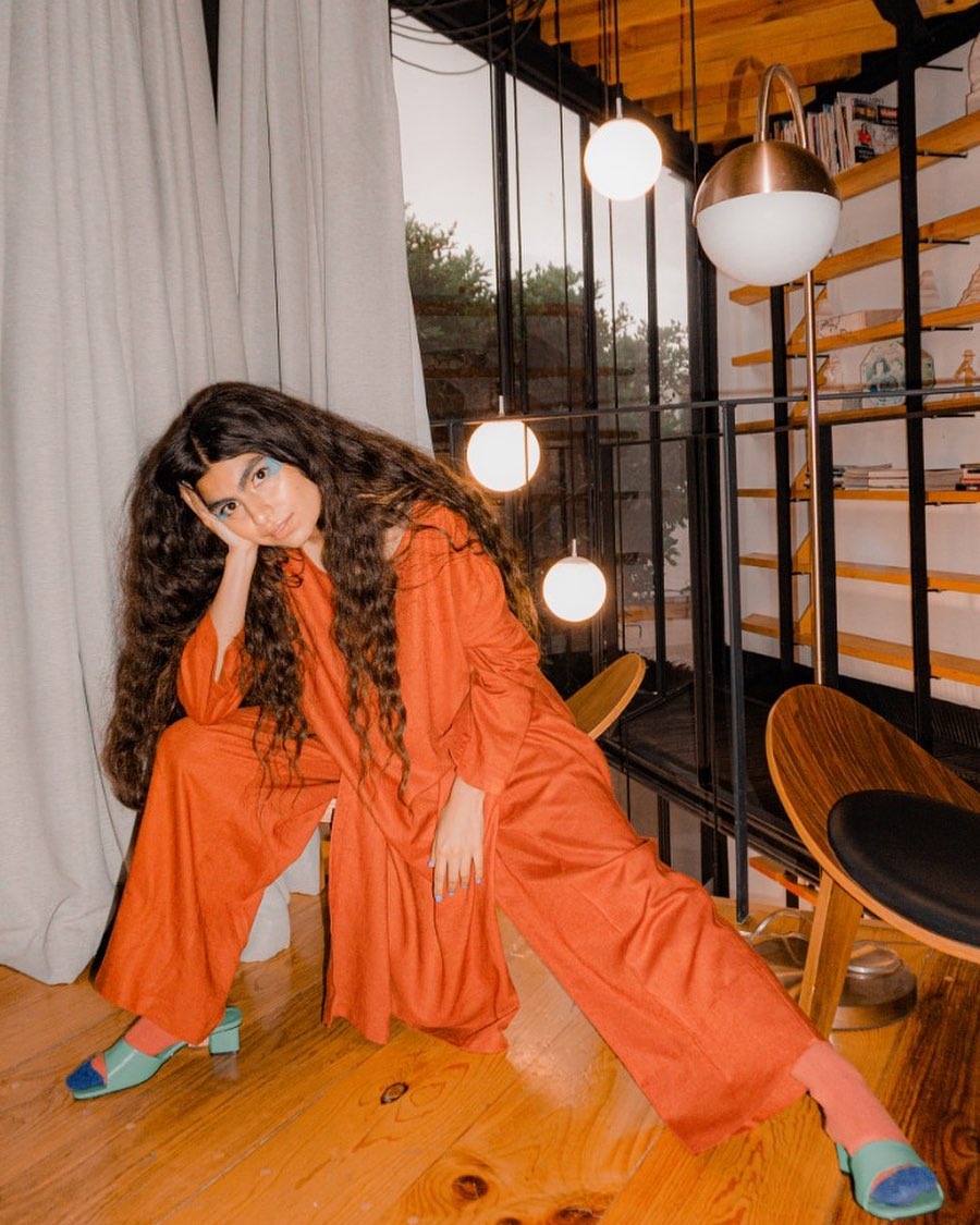mujer con traje naranja en un estudio de madera con ventana y arboles